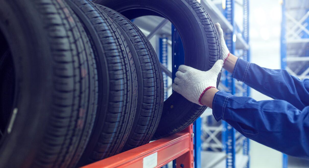 auto worker handling tires on tire rack