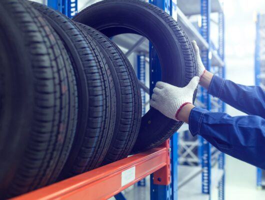 auto worker handling tires on tire rack