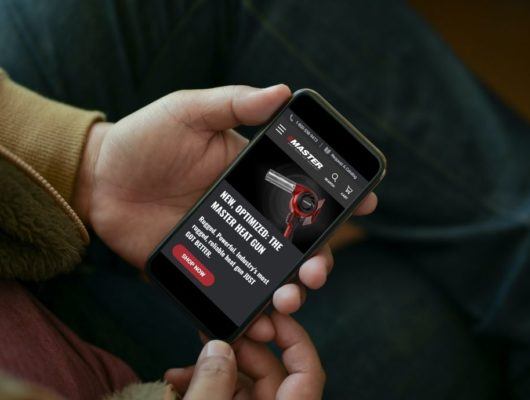 Man holding smartphone with MasterAppliance.com homepage on screen