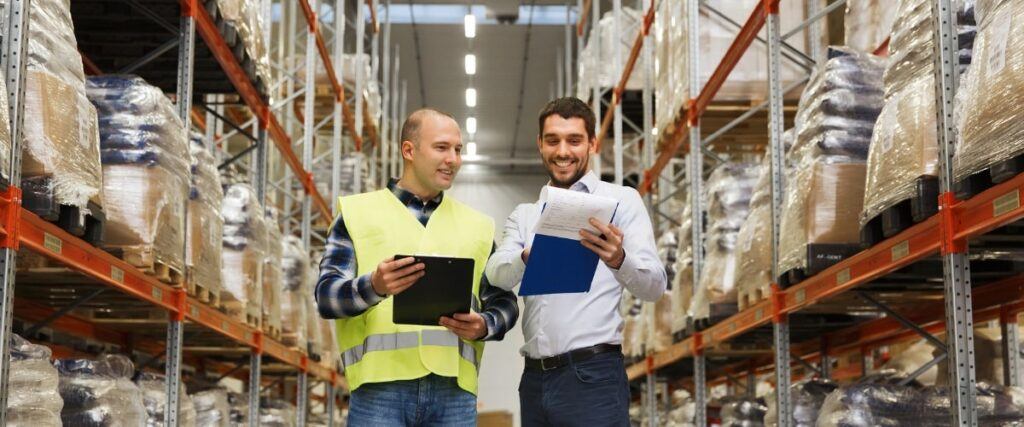 Two men in distribution warehouse discussing business