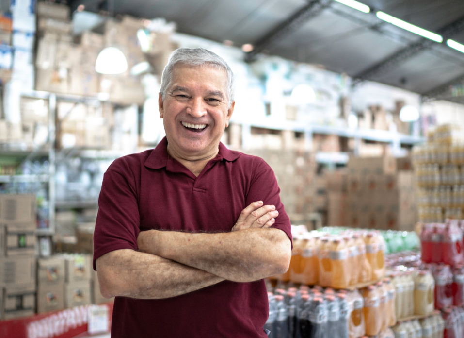 Man with crossed arms smiling in front of food distribution warehouse
