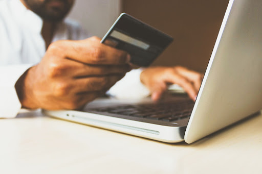 online shopping concept paying by credit card next to laptop