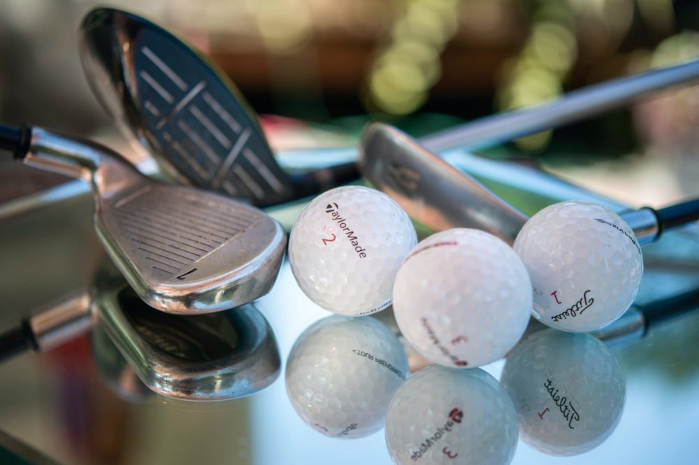 golf balls and clubs laying on reflective metal table