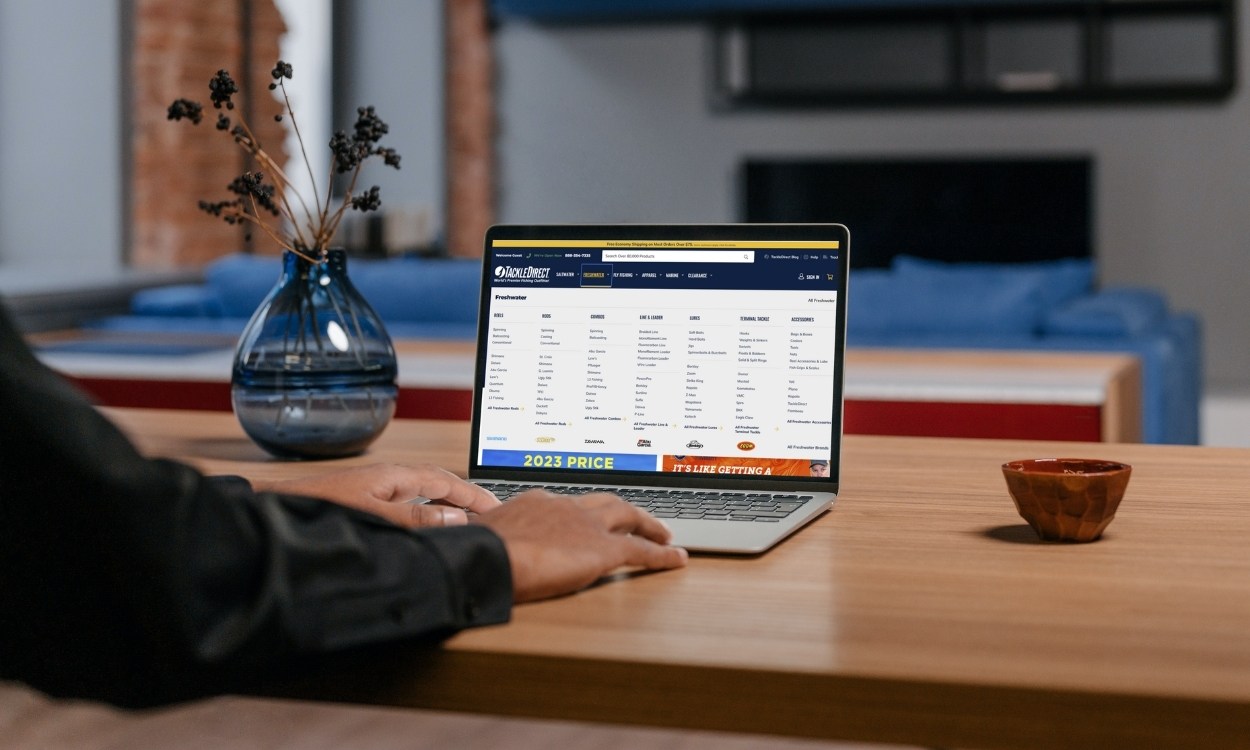 Man using laptop on table with TackleDirect.com on screen