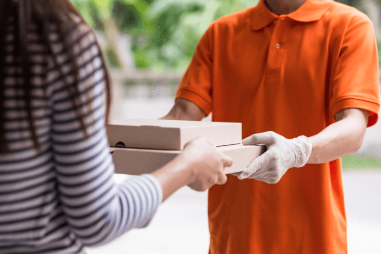 man in gloves handing home delivery of packages to woman