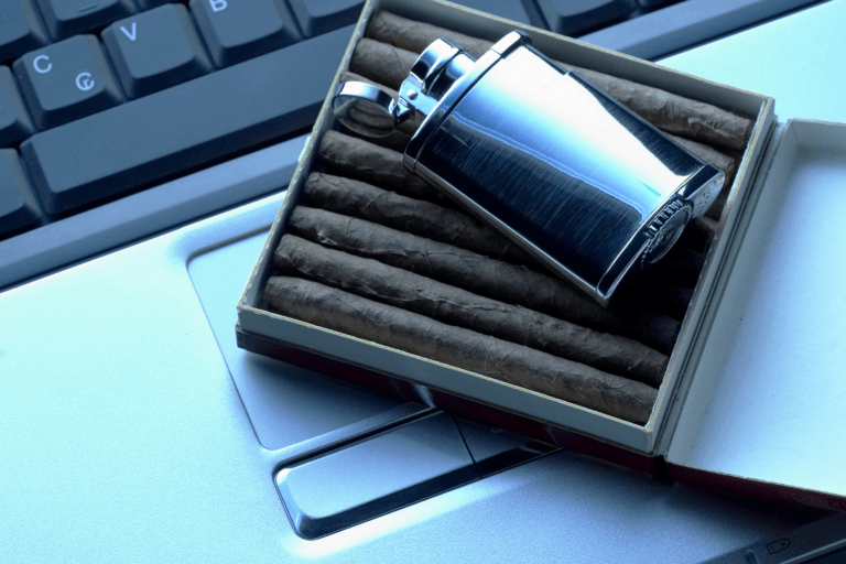 pack of cigars and lighter sitting on laptop