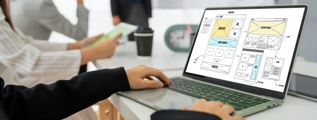 Person working on laptop with website wireframe on screen