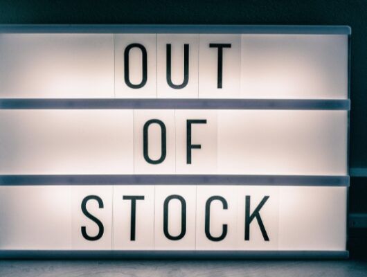 White outdoor sign saying "Out Of Stock" against dark background