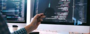 hand pointing to computer screen with computer code