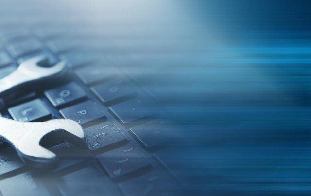 wrenches on keyboard over modern blue background