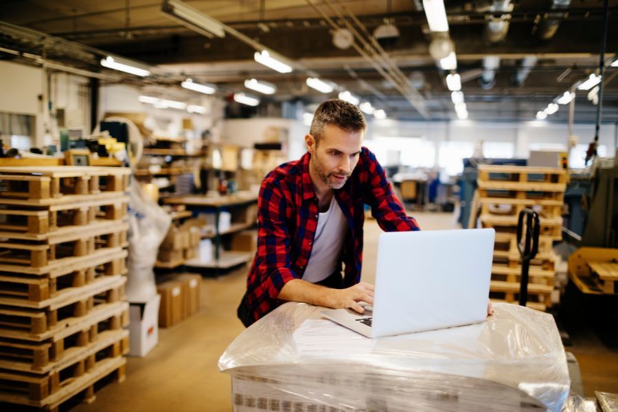 man in warehouse on laptop with pallets in background - BigCommerce redesign 3