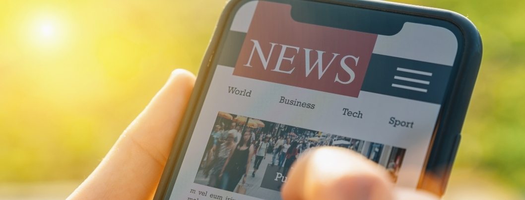 person holding mobile phone with news website on screen