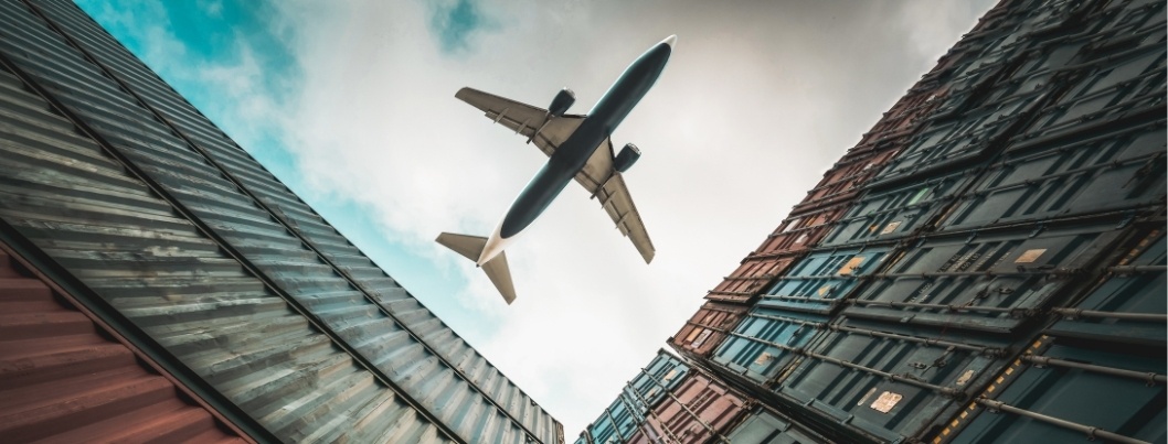 Freight airplane flying above overseas shipping container . Logistics supply chain management and international goods export concept.